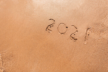 New Year 2021 is written on the beach sand by the sea. Travel season 2021 concept. Summer rest and vacation