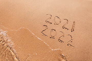 Inscription on the sand year numbers 2021 replace 2022 on the background of the wave view . Goodbye 2021 Hello 2022 happy new year concept. Text 2021 2022 on the beach. Summer rest