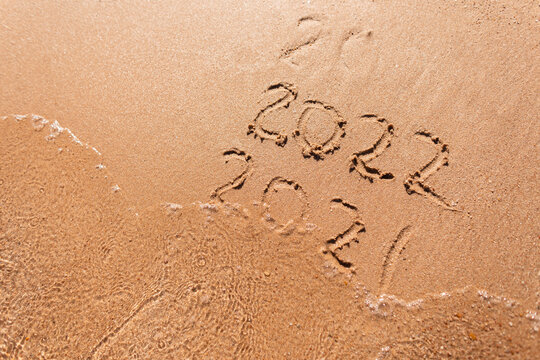 Message Year 2021 replaced by 2022 written on beach sand background. Good bye 2021 hello to 2022 happy New Year coming concept