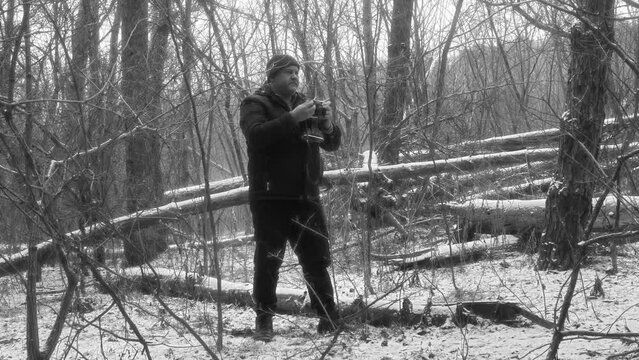 A tourist takes pictures on a retro film camera in a beautiful snowy forest in black and white
