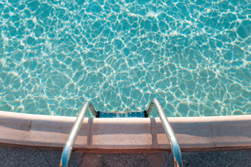 Beautiful pool with blue water and metal descent at sunset, top view. Rest, swimming, sports.