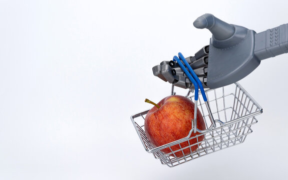 robot hand holds a grocery basket with an apple. food delivery using artificial intelligence. contactless trading.