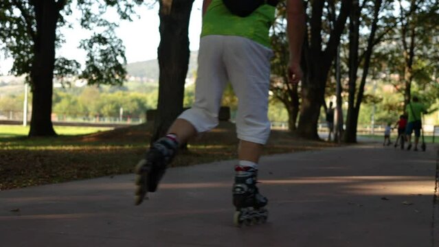 Close up of person roller skating through a city park. Cinematic tracking shot