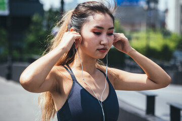 Sporty Woman Putting her Earphones On Before Running in the City