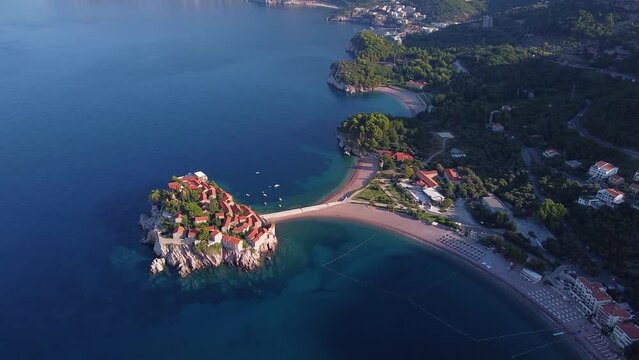Bird's eye view of coastal zone with beautiful island and bridge. Main tourist location in the region. Drone shot of Sveti Stefan (Saint Stephen) island in Montenegro.