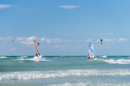 Surfer und Kiter auf der Ostsee in Warnem&uuml;nde im Sommer bei Sonnenschein