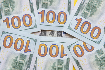 Franklin peeking through 100 dollar banknotes on yellow background