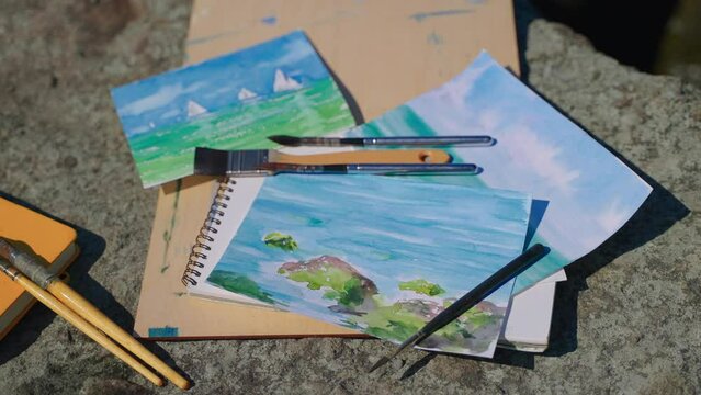 Finished watercolor seascapes and brushes outdoor