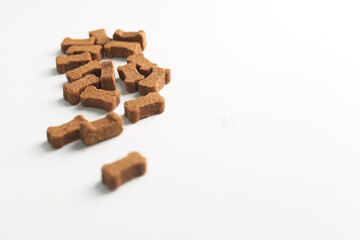 A stack of little beef dog treats shaped like little bones, tasty food for a puppy, white background