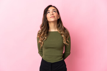 Young caucasian woman isolated on pink background and looking up