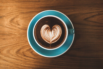 Coffee cup with latte art and heart shape foam on the wood table