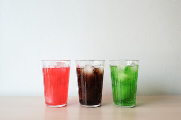 Glasses of soft drink with ice cubes and bubbles on wooden table kitchen background.