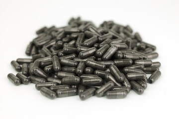 A pile of black medicine or health supplement pills on white background