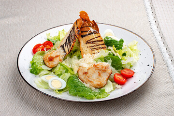 Caesar salad with chicken on a white decorative plate. A classic salad.