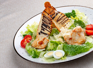 Caesar salad with chicken on a white decorative plate. A classic salad.
