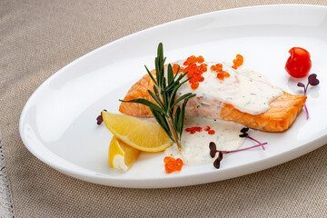 Salmon fillet with sauce and red caviar, rosemary and lemon.