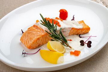 Salmon fillet with sauce and red caviar, rosemary and lemon.