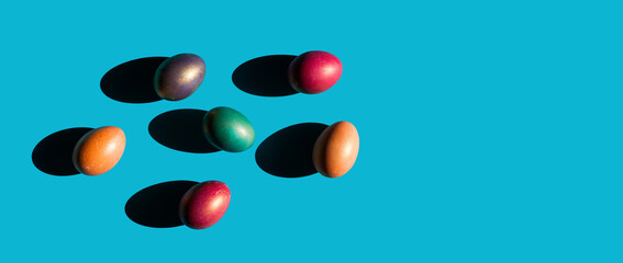 Happy Easter holiday concept. Set of handmade colorful eggs isolated on blue background with shadow. Simple trendy minimal composition, flat lay, top view, copy space, place for text, banner
