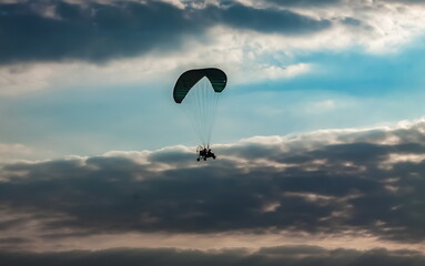 Paraglider on the background of a sunset sky with clouds in summer