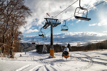 Empty chairs at station of ski-lift chair at resort Snowland Valca in winter season.