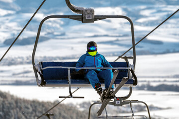 Fototapeta na wymiar Skier sitting on ski-lift chair or chairlift