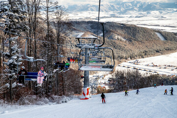 Skiers sitting on ski-lift chair or chairlift