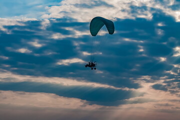Fototapeta na wymiar Paraglider on the background of a sunset sky with clouds in summer