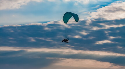 Paraglider on the background of a sunset sky with clouds in summer