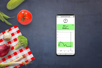 Mobile phone with measuring blood sugar level app using NFC sensors. Healthy food, vegetables beside. Top view, flat lay, composition