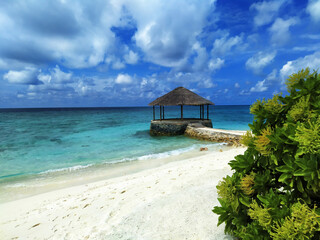 Maldives, the deserted beach with water cafe. A white sand, turquoise ocean and a blue sky.
