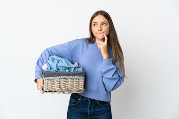 Young Lithuanian woman holding a clothes basket isolated on white background having doubts and thinking