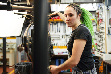 Woman repairing bicycle in workshop