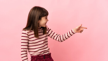 Little girl isolated on pink background pointing finger to the side and presenting a product