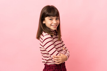 Little girl isolated on pink background looking to the side and smiling