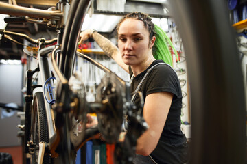 Female mechanic checking bicycle in garage