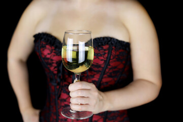 Glass of white wine in hand of sensual woman in red lace corset. Seductive female lingerie for celebration or romantic sex date