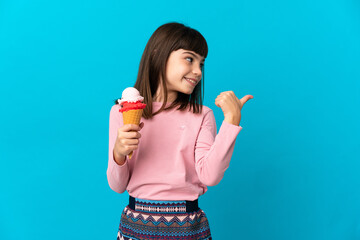 Little girl with a cornet ice cream isolated on blue background pointing to the side to present a product