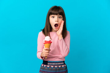Little girl with a cornet ice cream isolated on blue background with surprise and shocked facial...