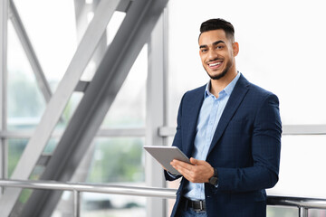 Naklejka na ściany i meble Modern Entrepreneurship. Handsome Arab Businessman With Digital Tablet Posing At Airport Terminal