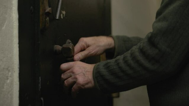Close up shot of an old man closing metal vintage old iron rusty door, film tone color. 