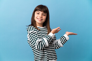 Little girl over isolated background holding copyspace imaginary on the palm to insert an ad