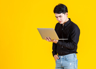 Portrait closeup studio shot of Asian man happy male businessman model in casual outfit standing holding laptop computer for advertising on yellow background