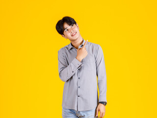 Studio shot of millennial Asian young male fashion model in stylish fashionable casual outfit standing on yellow background
