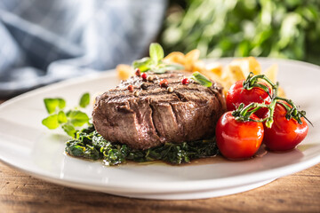 Well-done steak served with veggies on a plate ready to be eaten
