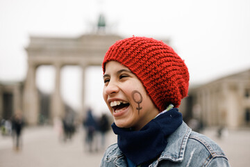 Girl in red cap smiling with face painted with female symbol