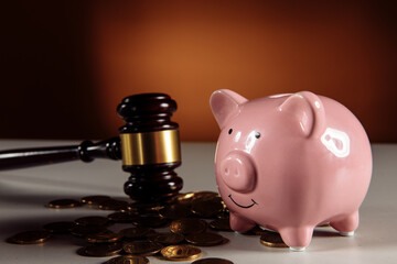Wooden gavel and pink piggy bank with coins. Business and bankruptcy concept