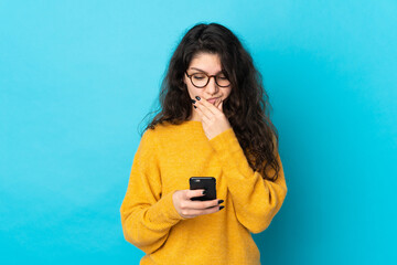 Teenager Russian girl isolated on blue background thinking and sending a message