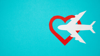Paper plane with red heart shape on blue background. Copy space for text.