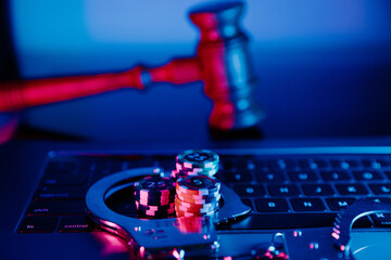Handcuffs, gavel and chips on a laptop. Online casino concept