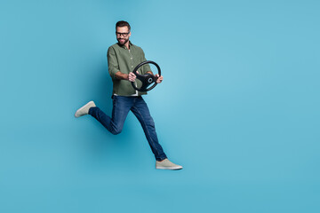 Full size photo of cheerful handsome male jumping traveling hold car steering wheel isolated on blue color background
